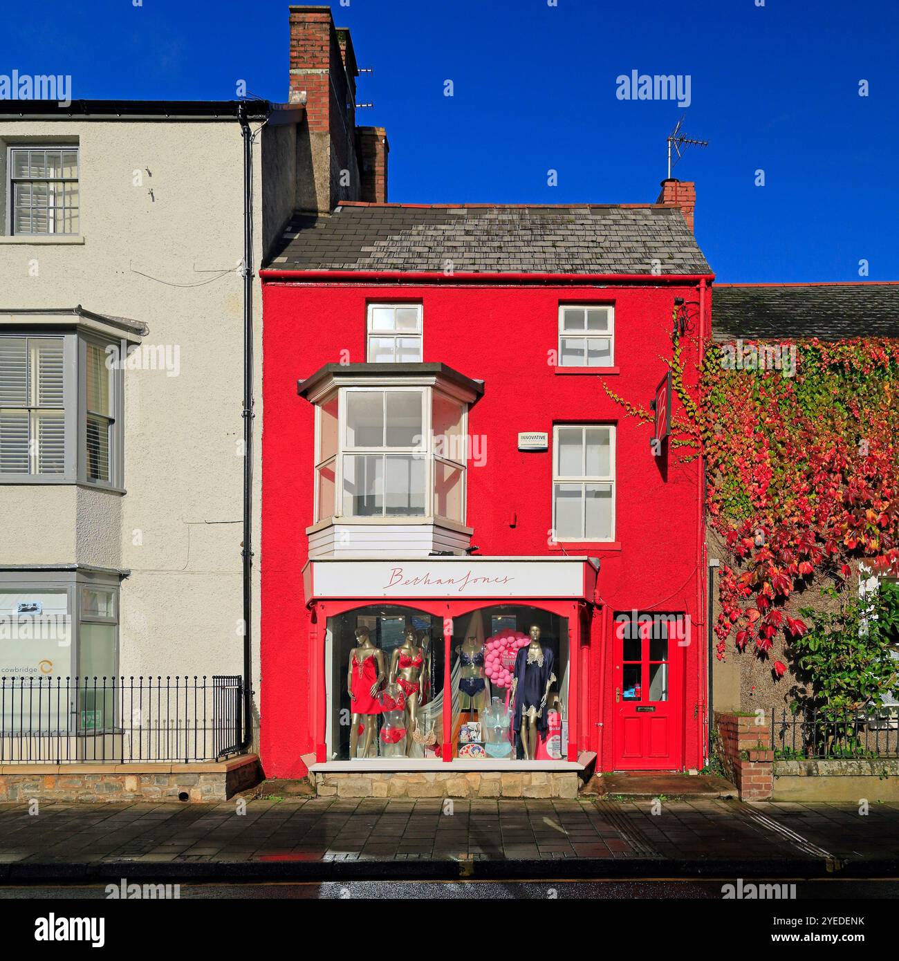 Boutique rouge brillamment peinte, High Street et route principale à travers Cowbridge, Vale of Glamorgan, South Wales, Royaume-Uni. Octobre 2024. Automne Banque D'Images