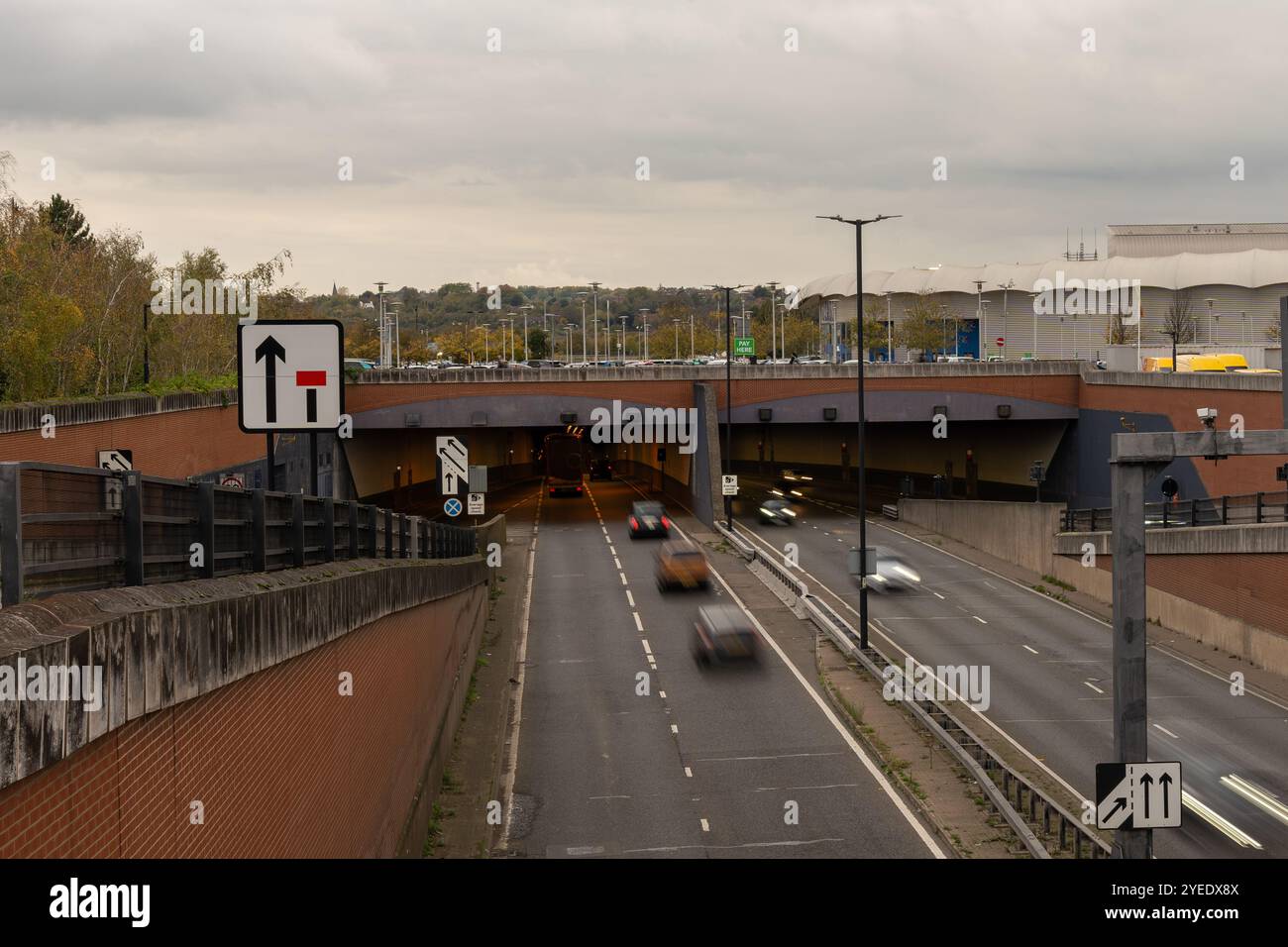 Voitures floues circulant sur une route entrant et sortant d'un tunnel, sous un parking et près de l'aréna ricoh à coventry, en angleterre Banque D'Images