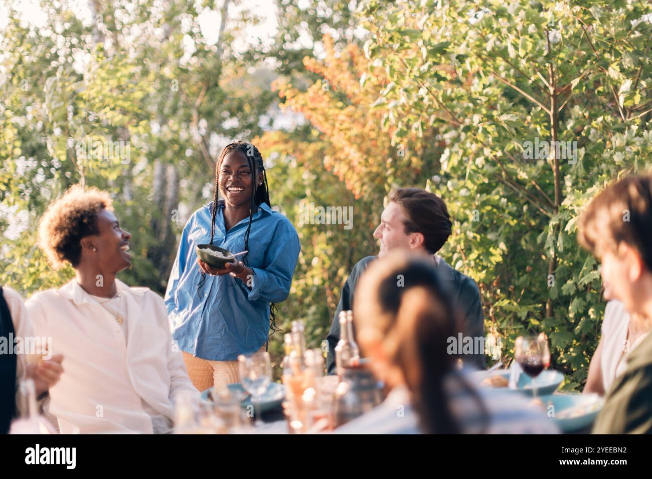 Femme souriante appréciant avec un groupe d'amis dans le dîner à l'arrière-cour Banque D'Images