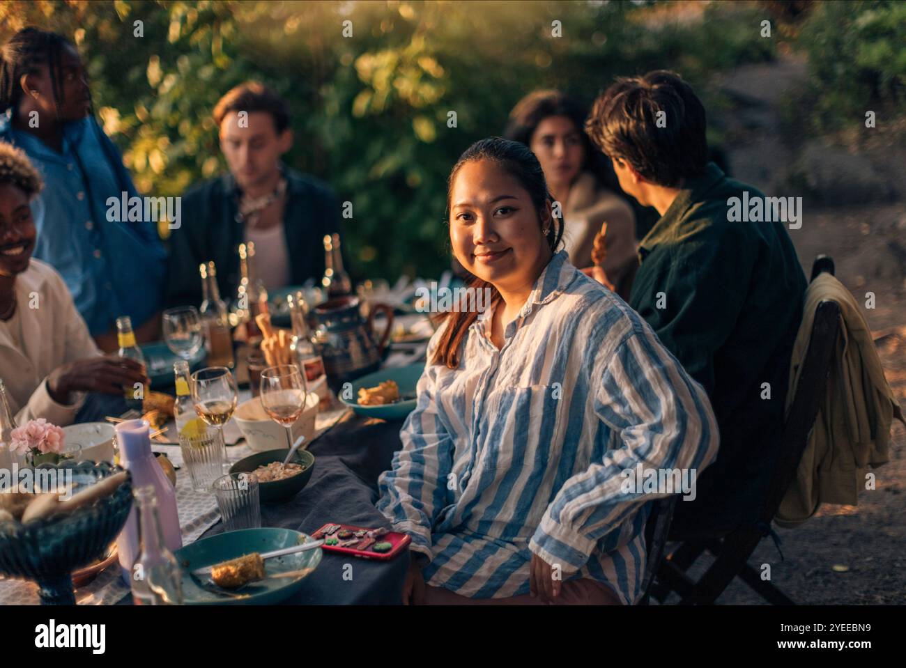 Portrait de femme souriante assise avec des amis à la table à manger pendant la fête dans la cour arrière Banque D'Images