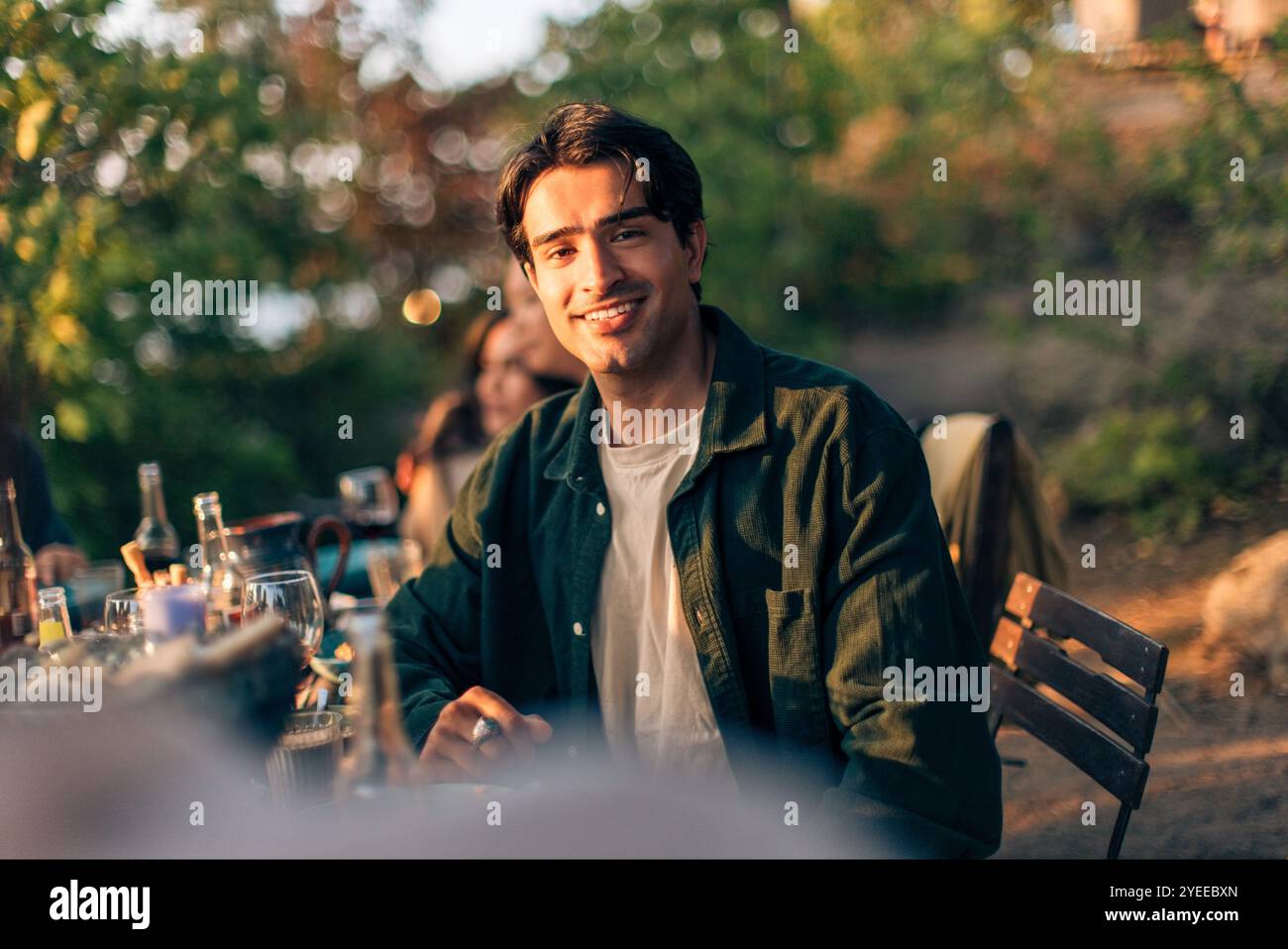 Portrait d'homme souriant en veste denim assis à la table à manger pendant le dîner Banque D'Images