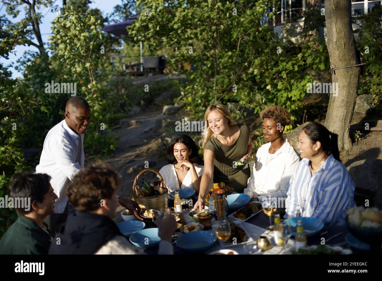 Groupe d'amis masculins et féminins multiraciaux ayant de la nourriture et des boissons au dîner dans la cour arrière Banque D'Images