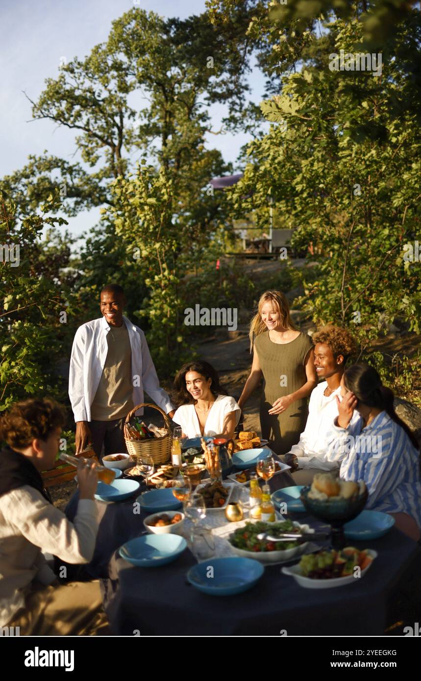 Groupe d'amis heureux assis dans la cour arrière tout en célébrant pendant le dîner Banque D'Images