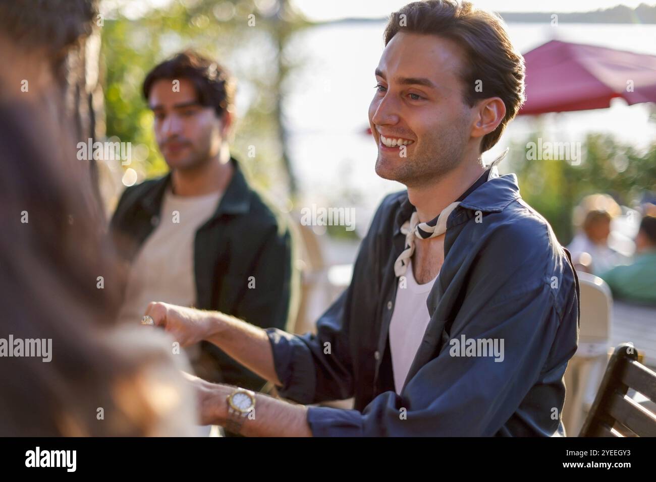 Jeune homme souriant passant du temps libre avec des amis au dîner Banque D'Images