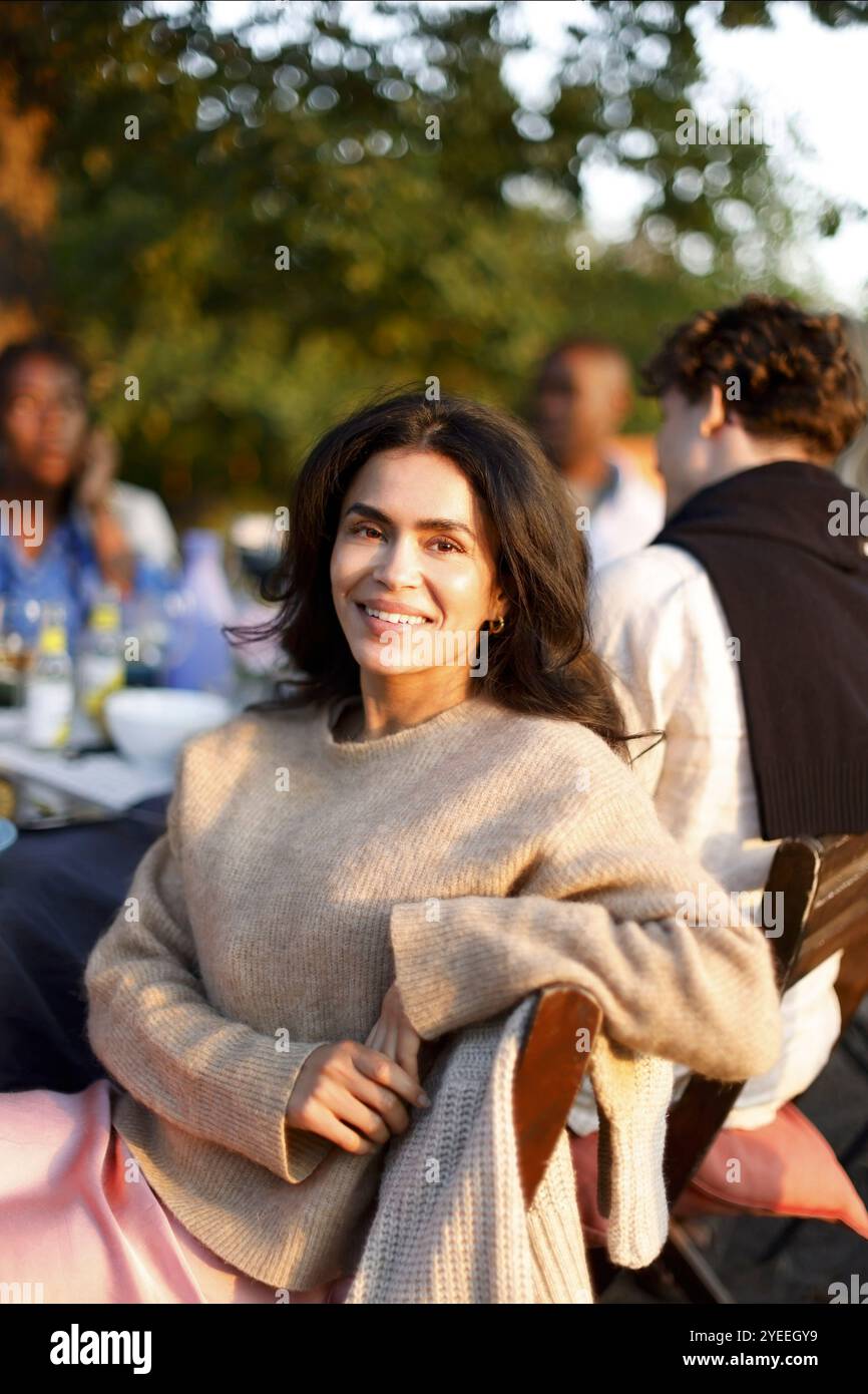 Portrait d'une femme souriante assise sur une chaise lors d'un événement social Banque D'Images