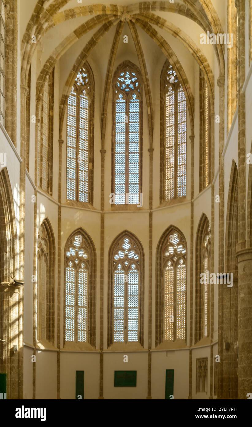 La lumière du soleil traverse les vitraux, mettant en valeur le superbe design gothique de l'intérieur de l'église. Banque D'Images