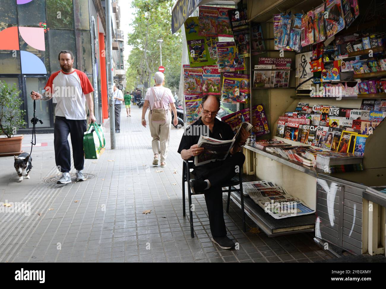 Un catalan lisant le journal près d'un stand de magazine sur Carrer de Còrsega, Gràcia, Barcelone, Espagne. Banque D'Images