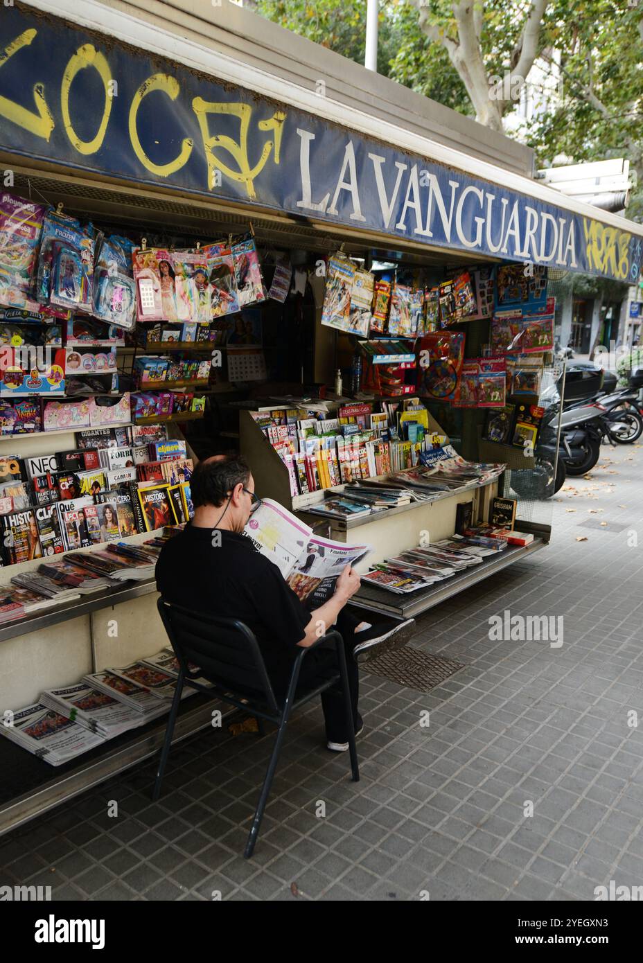 Un catalan lisant le journal près d'un stand de magazine sur Carrer de Còrsega, Gràcia, Barcelone, Espagne. Banque D'Images
