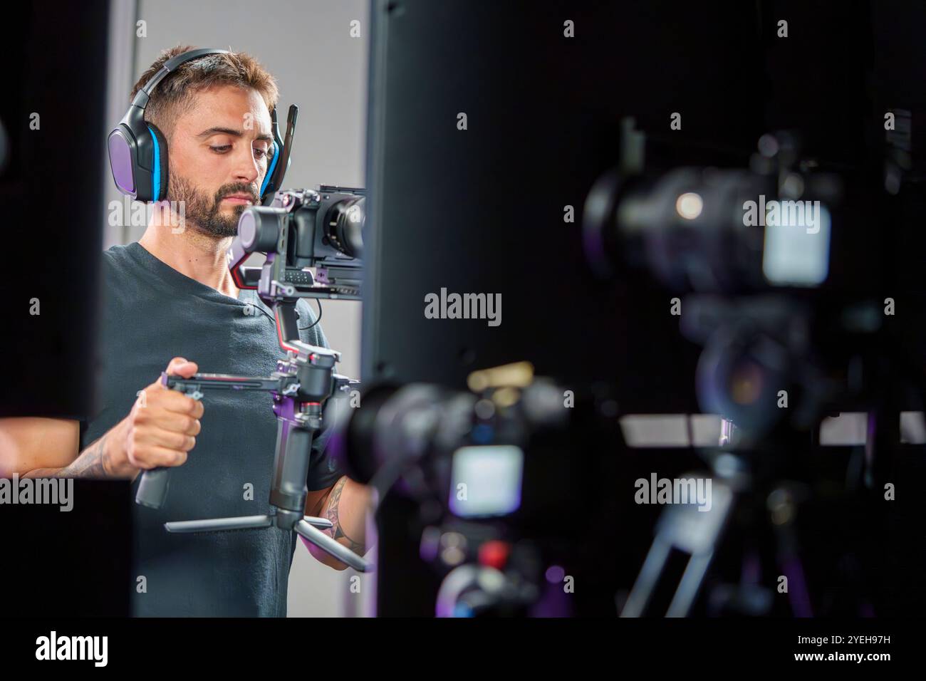 Jeune caméraman masculin utilisant une nacelle pour filmer sur un téléviseur professionnel avec casque Banque D'Images