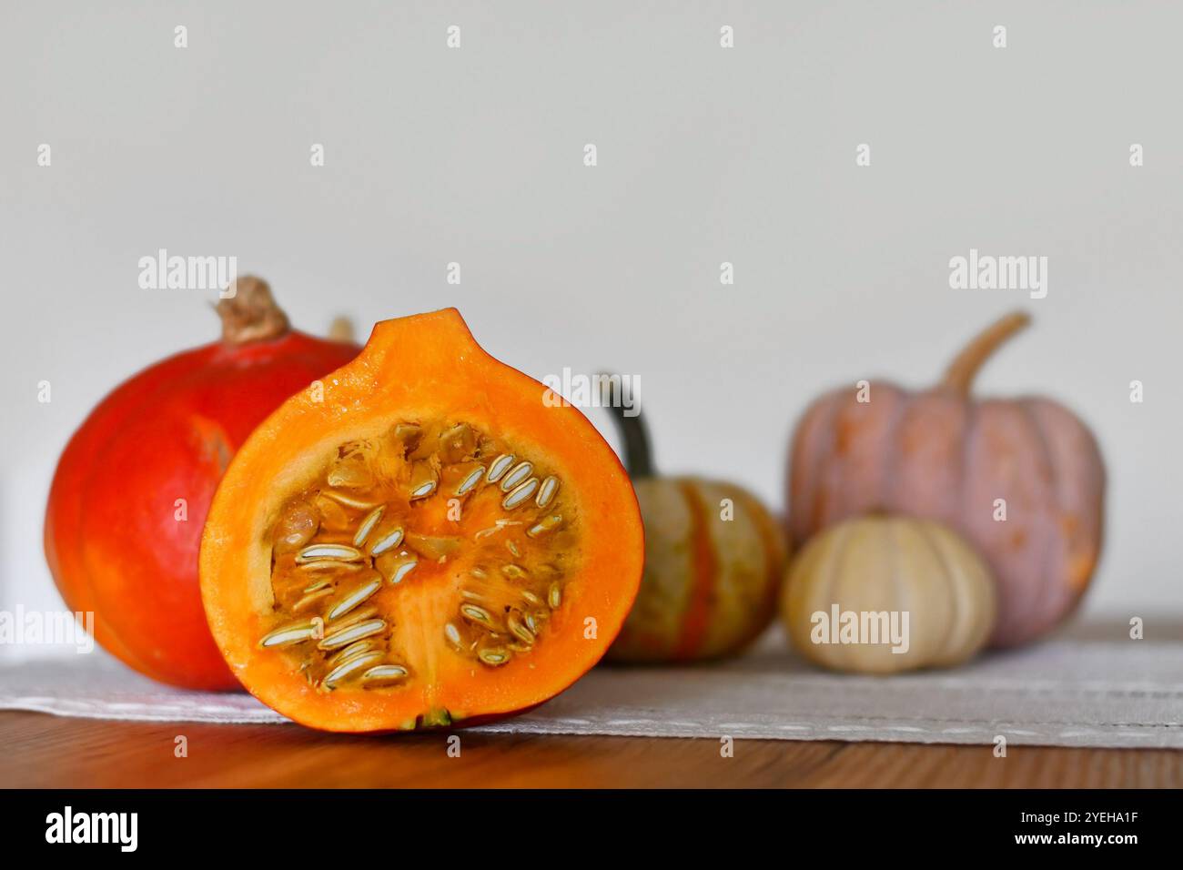 Citrouille Hokkaido coupée en deux montrant des graines avec d'autres citrouilles en arrière-plan Banque D'Images