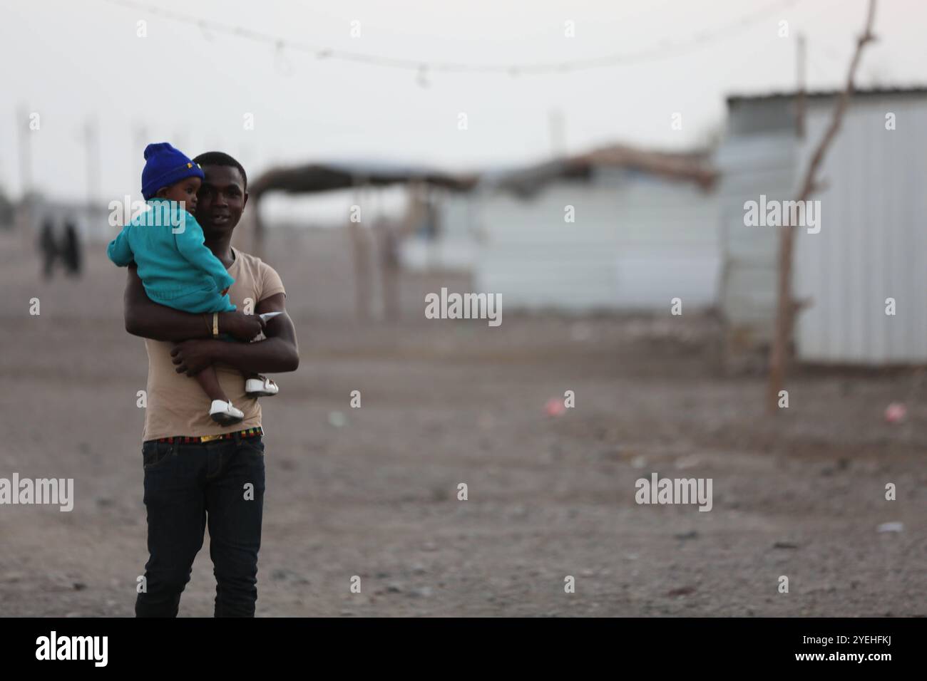 Basateen est un quartier de banlieue près de la ville d'Aden. Elle est habitée par environ 40 000 personnes, dont 30% sont des réfugiés somaliens. Basateen est l'une des régions les plus sous-développées du Yémen, qui manque de services et d'infrastructures de base. Les maisons de fortune construites au hasard par les habitants eux-mêmes sont entourées de tas d'ordures. Les services d'assainissement, y compris le système d'égouts, sont extrêmement élémentaires et il existe de graves risques de maladies endémiques. Le quartier Basateen avait déjà grand besoin d'amélioration des infrastructures d'eau, d'assainissement, de santé et d'éducation Banque D'Images