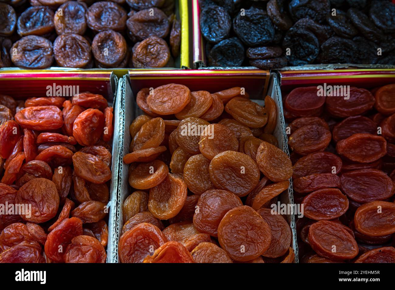 Abricots secs orange et foncés dans des boîtes à vendre au marché, vue de dessus. Fruits séchés, abricots séchés comme fond. Banque D'Images