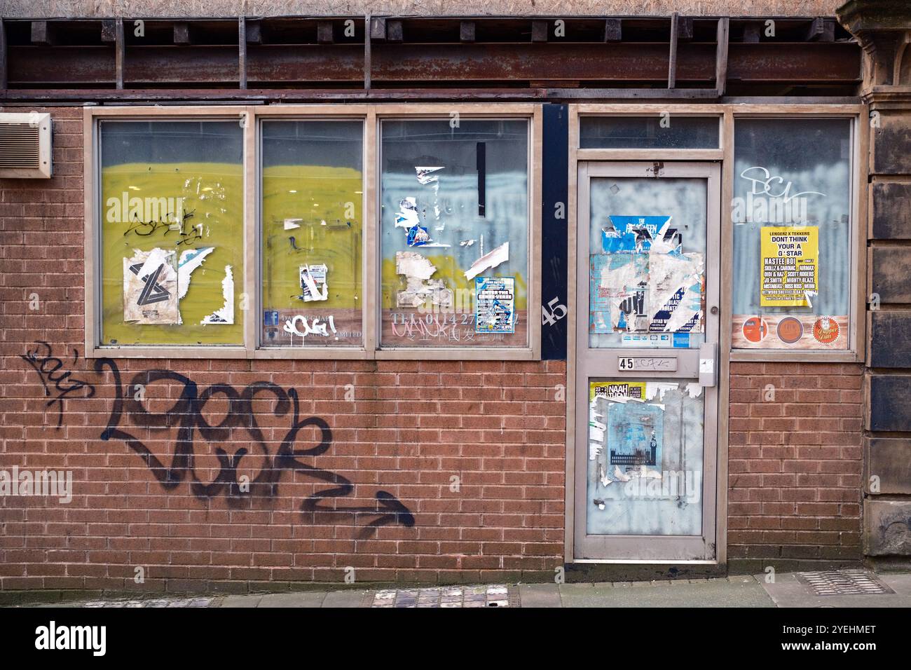 Un magasin abandonné et vide à Sheffield, en Angleterre. La boutique, photographiée en 2024 et auparavant coiffeuse, a été occupée pour la dernière fois vers 2016. Les fenêtres ont été vidées, avec de vieilles affiches et quelques graffitis également visibles. Banque D'Images