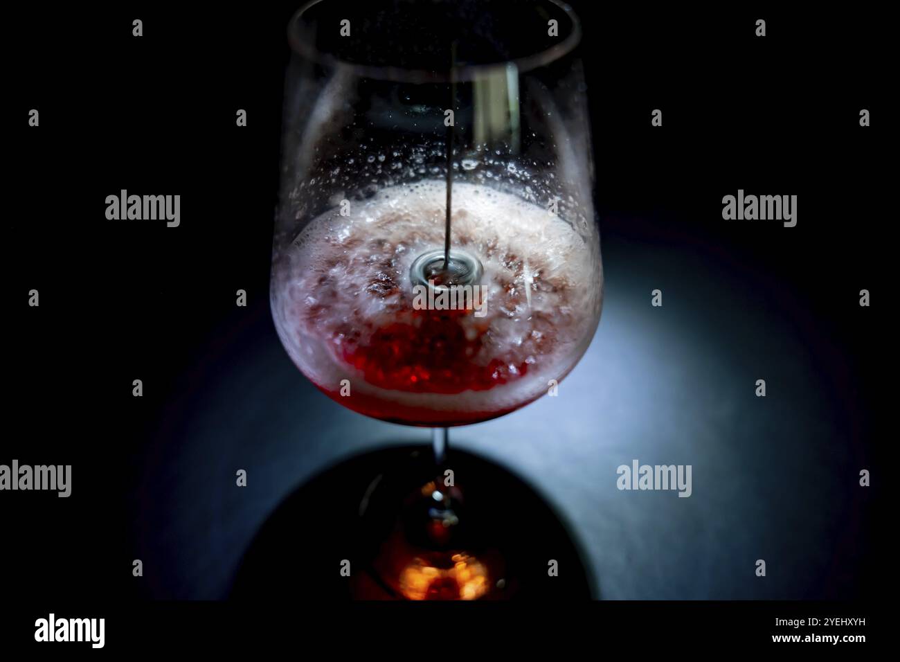 Utiliser un mélangeur électrique dans un verre à vin avec du vin rose pour enlever les sulfites dangereux en Suisse Banque D'Images