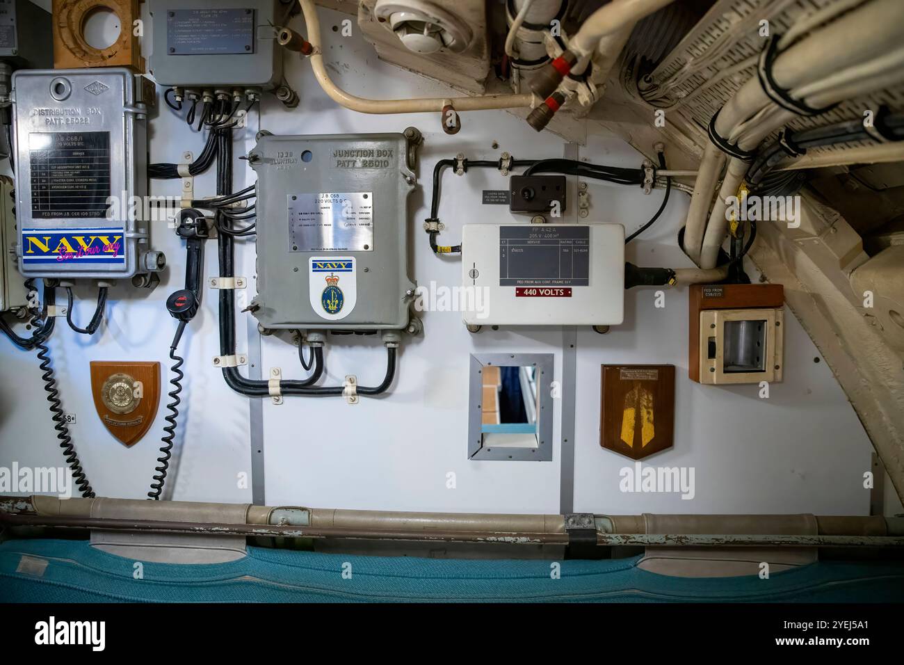 Cette photographie représente une partie du mur intérieur d'un sous-marin présentant diverses boîtes de jonction, des panneaux étiquetés et du matériel de commande électrique. Banque D'Images