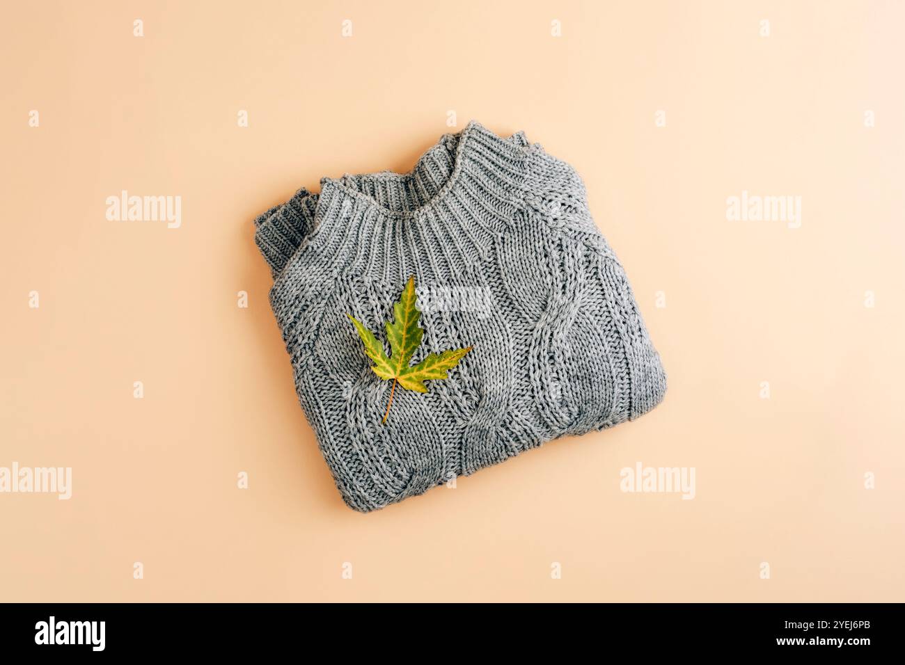 Pull tricoté gris et feuille d'automne sur fond beige. Shopping, concept de vente saisonnière. Vue de dessus, pose à plat. Banque D'Images
