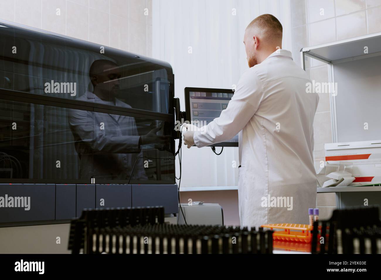 Scientifique travaillant dans un environnement de laboratoire stérile, examinant les données sur écran d'ordinateur tout en utilisant des appareils de laboratoire avancés dans un espace de travail propre et organisé Banque D'Images