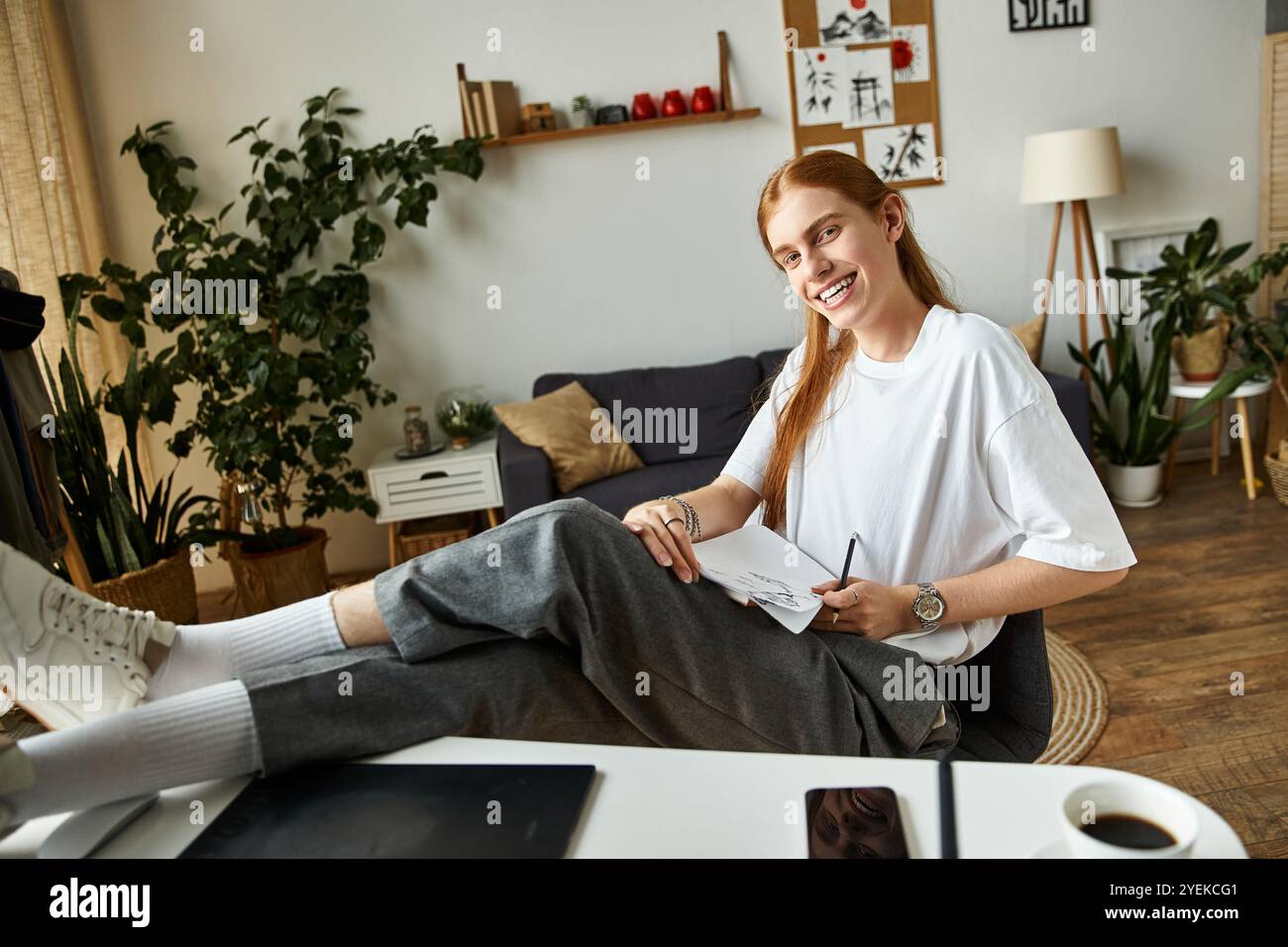 Un jeune homme capte l'inspiration tout en étant confortablement assis dans un espace de travail élégant et lumineux. Banque D'Images