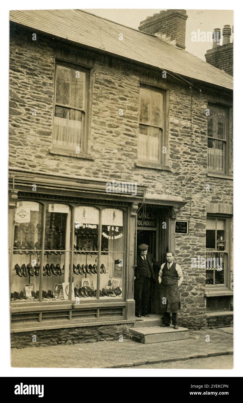 Début des années 1920 carte postale des commerçants devant leur petite boutique indépendante. F. & S. Jones bottes et chaussures magasin est le signe dans la vitrine du magasin. Ces propietors de magasin de chaussures font la publicité des chaussures de créateurs de Grenson. Bristol House, Pembroke, pays de Galles, Royaume-Uni Banque D'Images