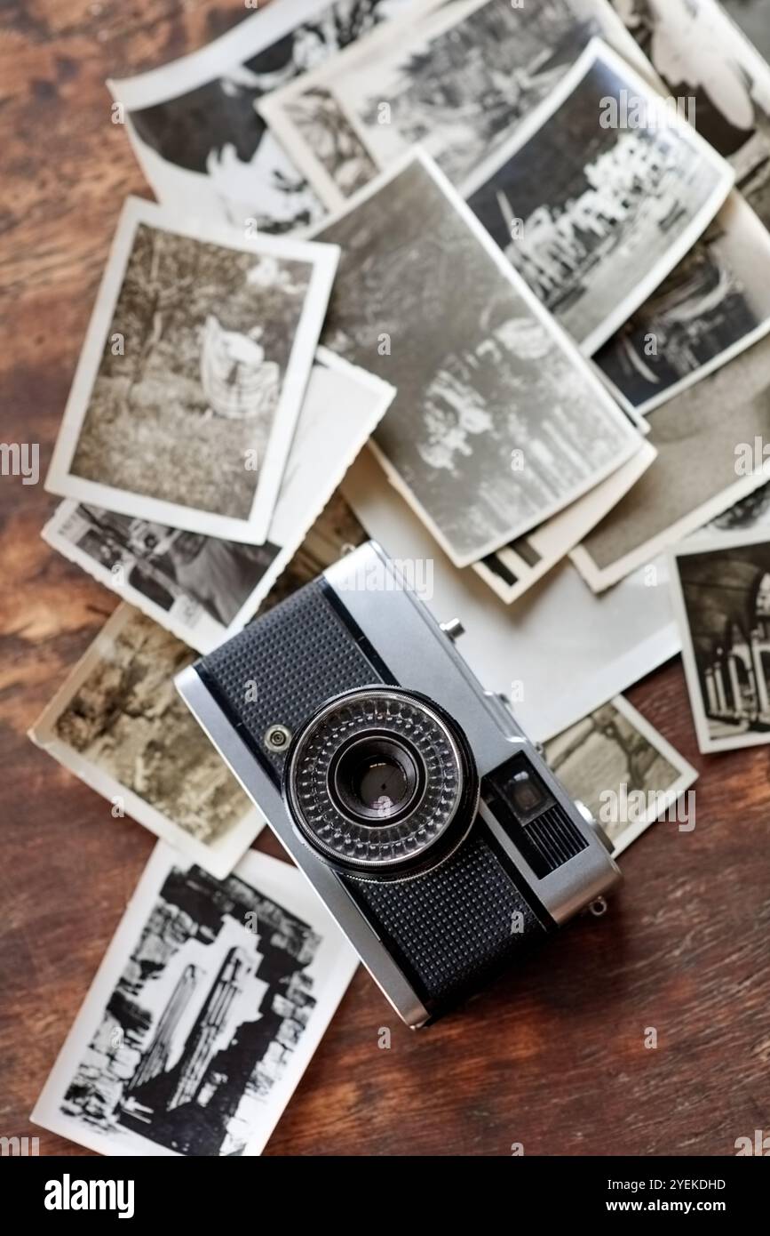 Bureau en bois, vintage et appareil photo avec des photographies rétro sur noir et blanc. Numérique, old School et table avec des images pour la créativité, le projet et Banque D'Images