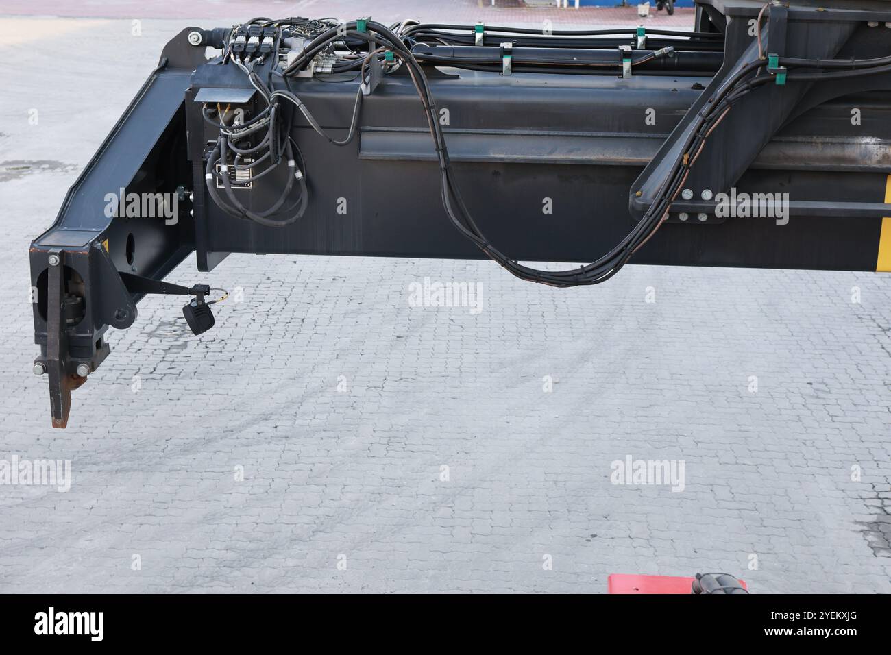 Vue détaillée du bras mécanique d'un gerbeur télescopique chargé avec flexibles hydrauliques sur une surface en béton. Banque D'Images