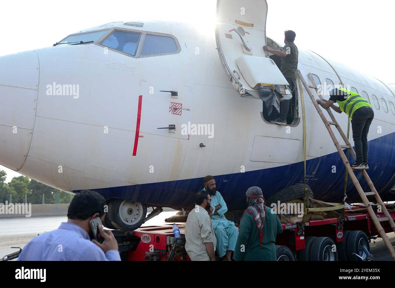 Vue d'un grand avion de passagers est transporté de Karachi à Hyderabad par la route, l'avion a été chargé sur un conteneur puis déplacé sur l'autoroute, à la route Super Highway à Karachi le jeudi 31 octobre 2024. Un avion est transporté par route de Karachi à Hyderabad pour la première fois dans l'histoire. Une société de transport privée entreprend cette opération unique, en utilisant un camion de 10 roues et une remorque de 40 roues pour déplacer un Boeing 737 non fonctionnel. Banque D'Images