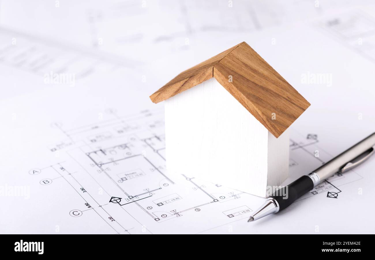 Un concept de demande de permis de construire, avec un modèle de maison et des plans de construction placés sur une table, symbolisant le processus de planification et ap Banque D'Images