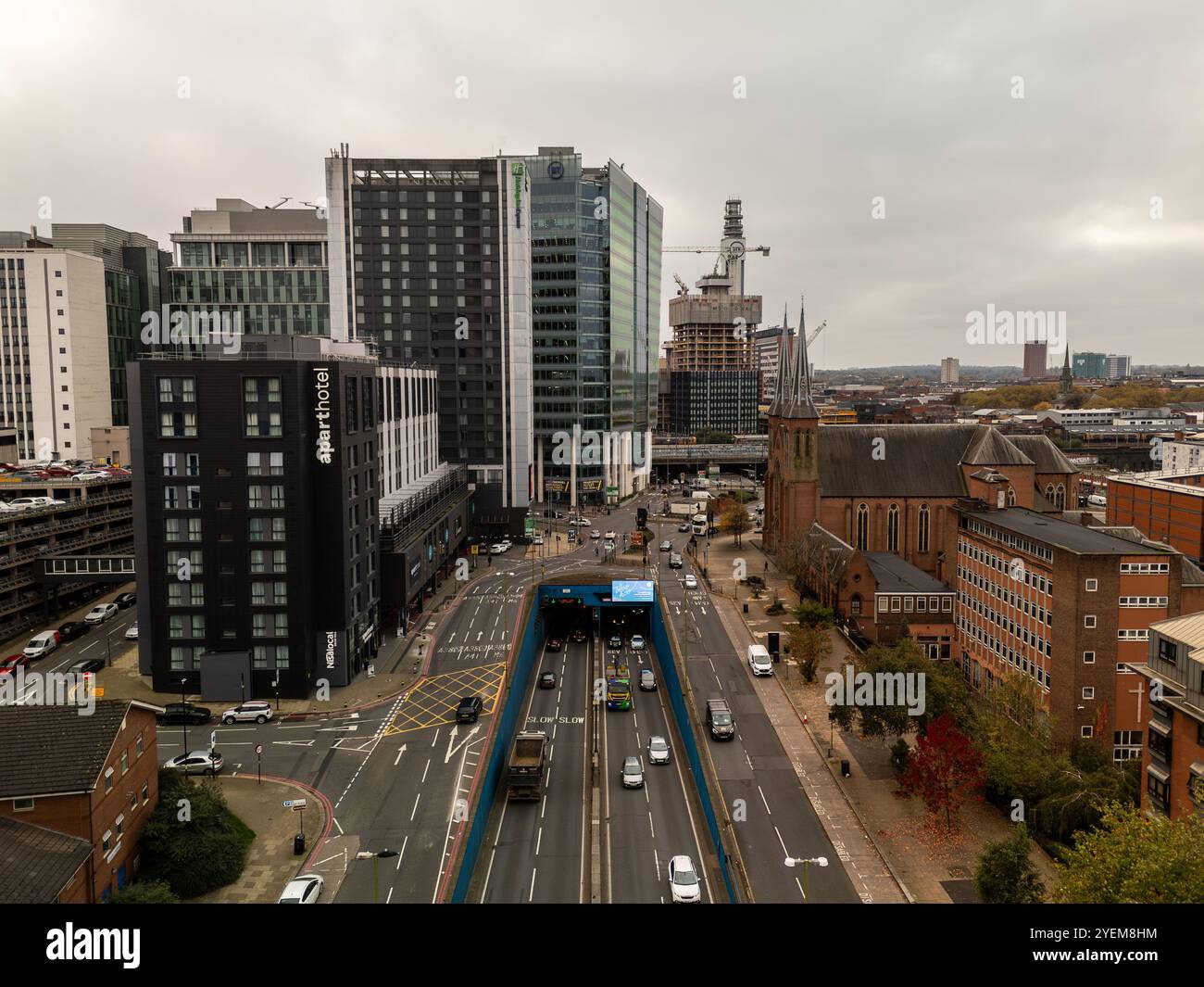 Vue aérienne du centre-ville de birmingham montrant le trafic naviguant dans un tunnel, des bâtiments modernes et une église, symbolisant le mélange de l'ancien et du nouvel arc Banque D'Images