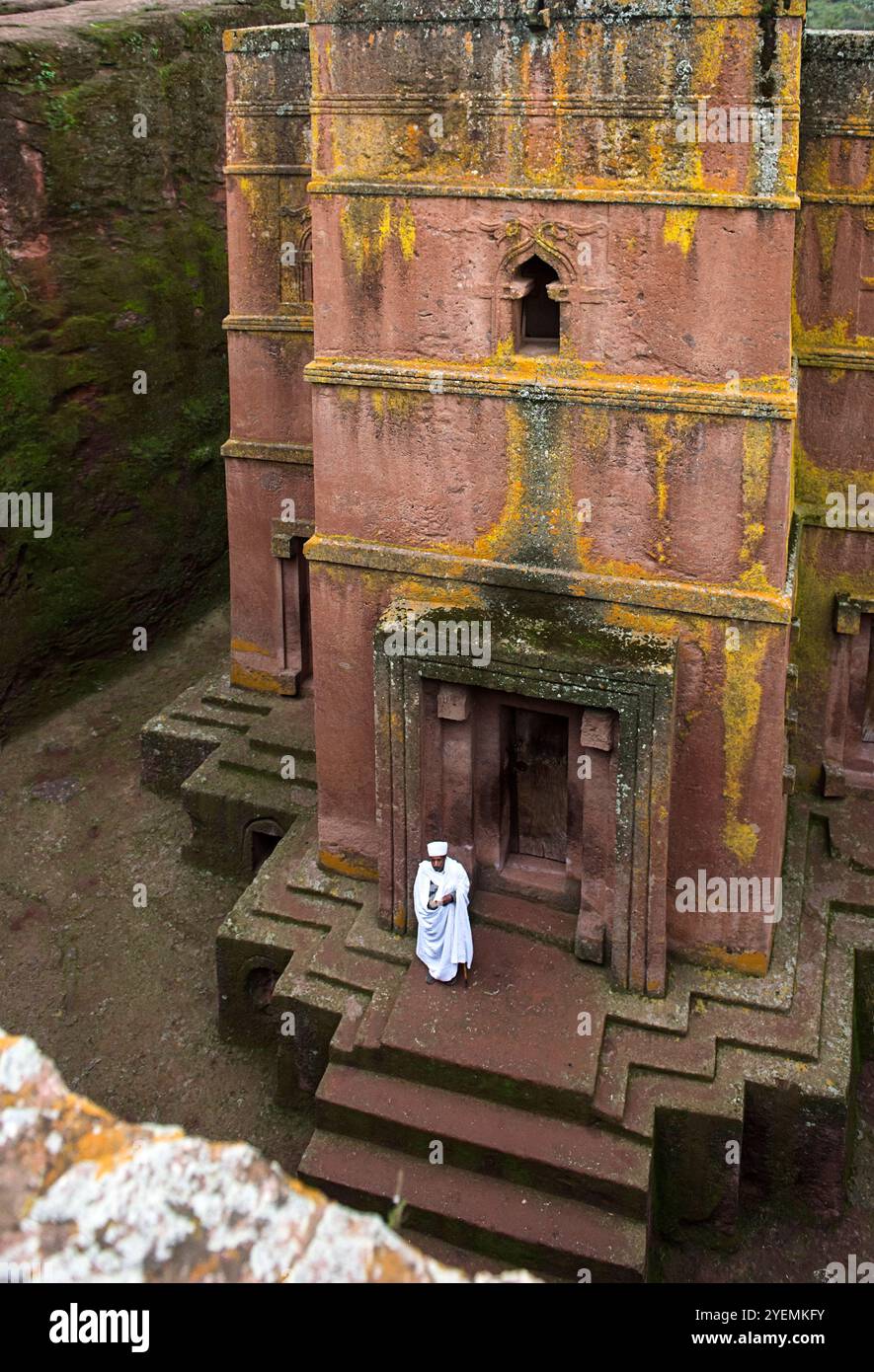 Prêtre éthiopien à l'entrée de l'église souterraine monolithique taillée dans la roche de Biete Giyorgis, site du patrimoine mondial de l'UNESCO à Lalibela, Ethiopie Banque D'Images
