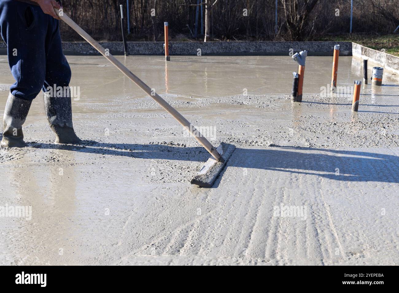 Ouvrier constructeur lissant le béton beton d'une dalle sur un chantier de construction Banque D'Images
