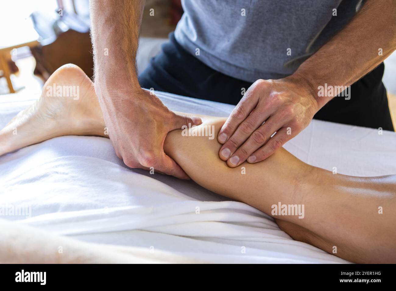 Jeune masseuse expérimentée faisant un massage thérapeutique. Travail de masseur. Massage au spa dans un cadre confortable. Traitement de massage des jambes à l'huile Banque D'Images