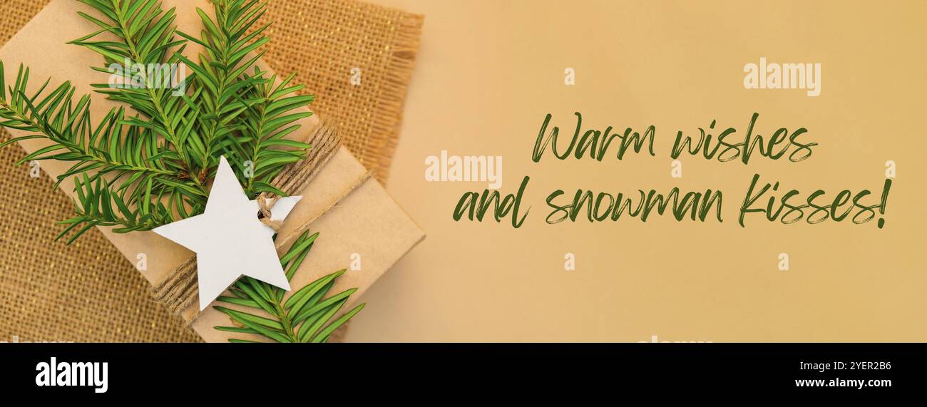 Voeux chaleureux et bonhomme de neige inspiration baiser citation phrase Box avec les cadeaux du nouvel an, enveloppé dans du papier artisanal et décoré avec une branche de sapin. Vacances Banque D'Images