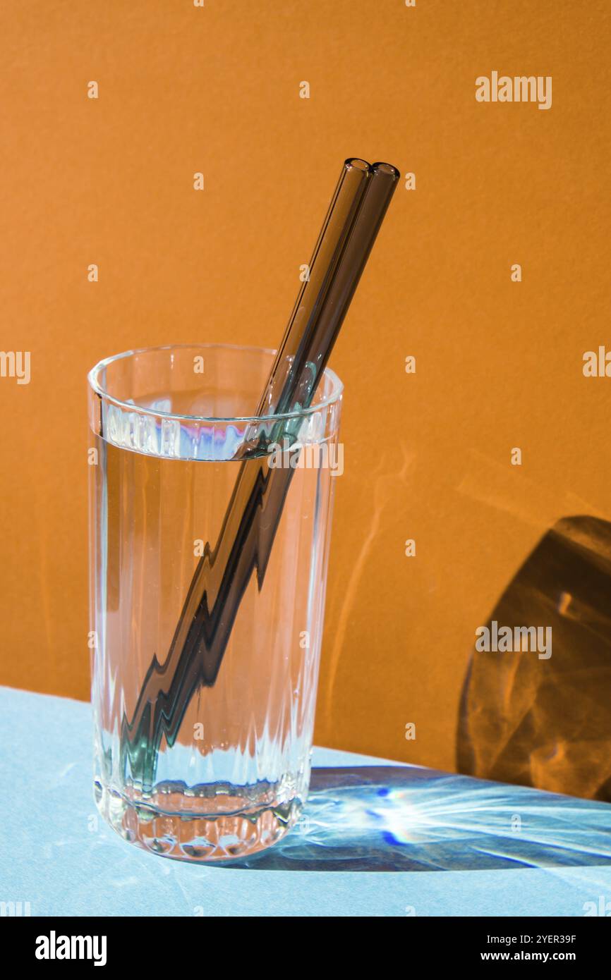 Pailles en verre réutilisables en verre avec eau sur fond coloré ensemble de pailles écologiques avec brosse de nettoyage. Concept sans déchets, sans plastique Banque D'Images