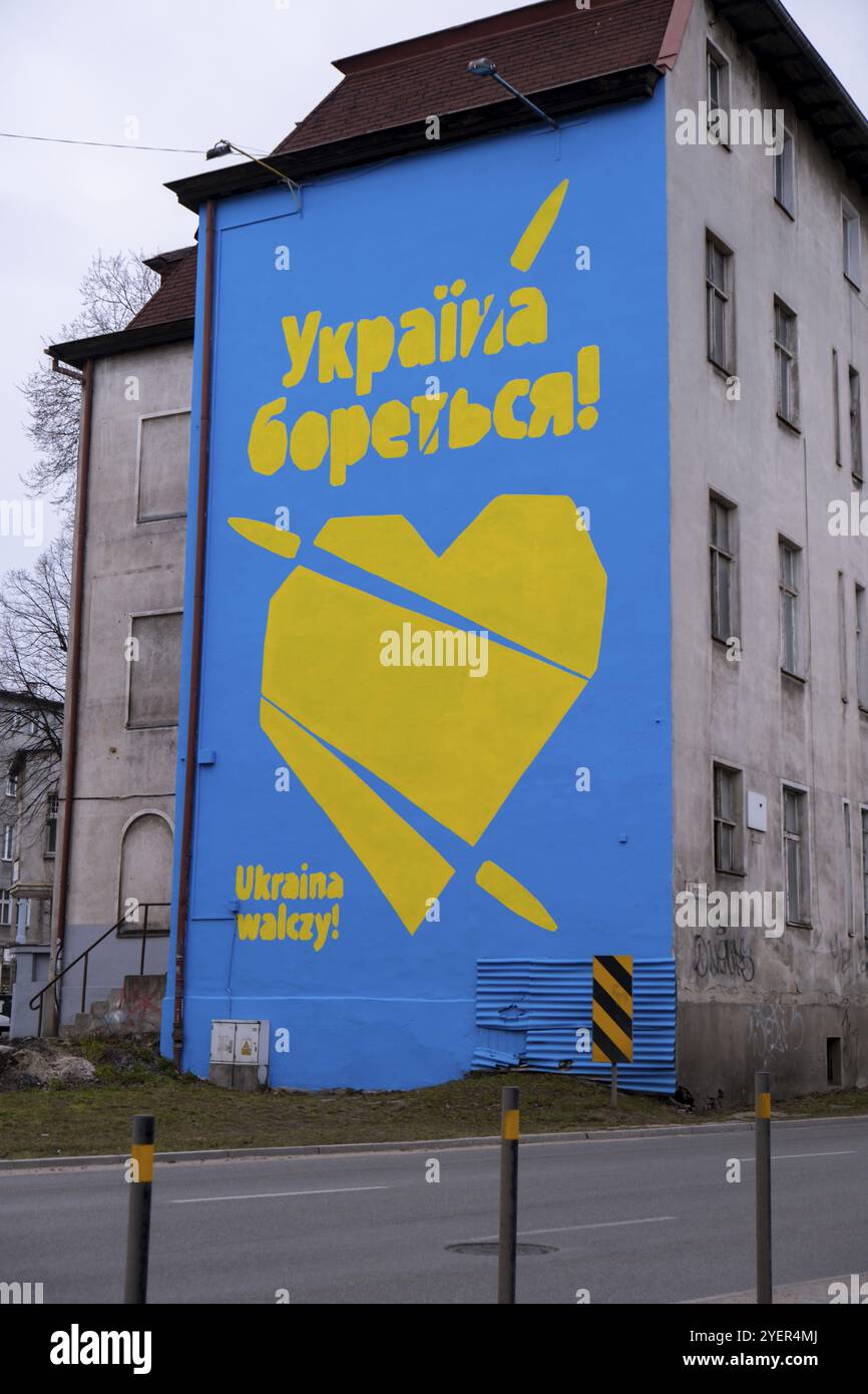 Gdansk Pologne Mars 2022 UKRAINE COMBAT le texte EN GRAFFITI avec grand coeur dans les couleurs du drapeau ukrainien. Peinture murale dans la maison de bâtiment Pologne Gdansk Euro Banque D'Images