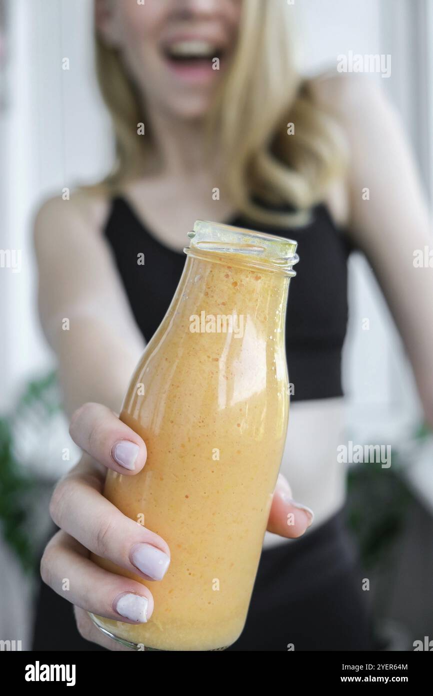 Jeune femme blonde millénelle boit du smoothie végétalien Detox. Femme faisant des exercices de yoga à la maison. Alimentation propre, perte de poids, alimentation saine c Banque D'Images