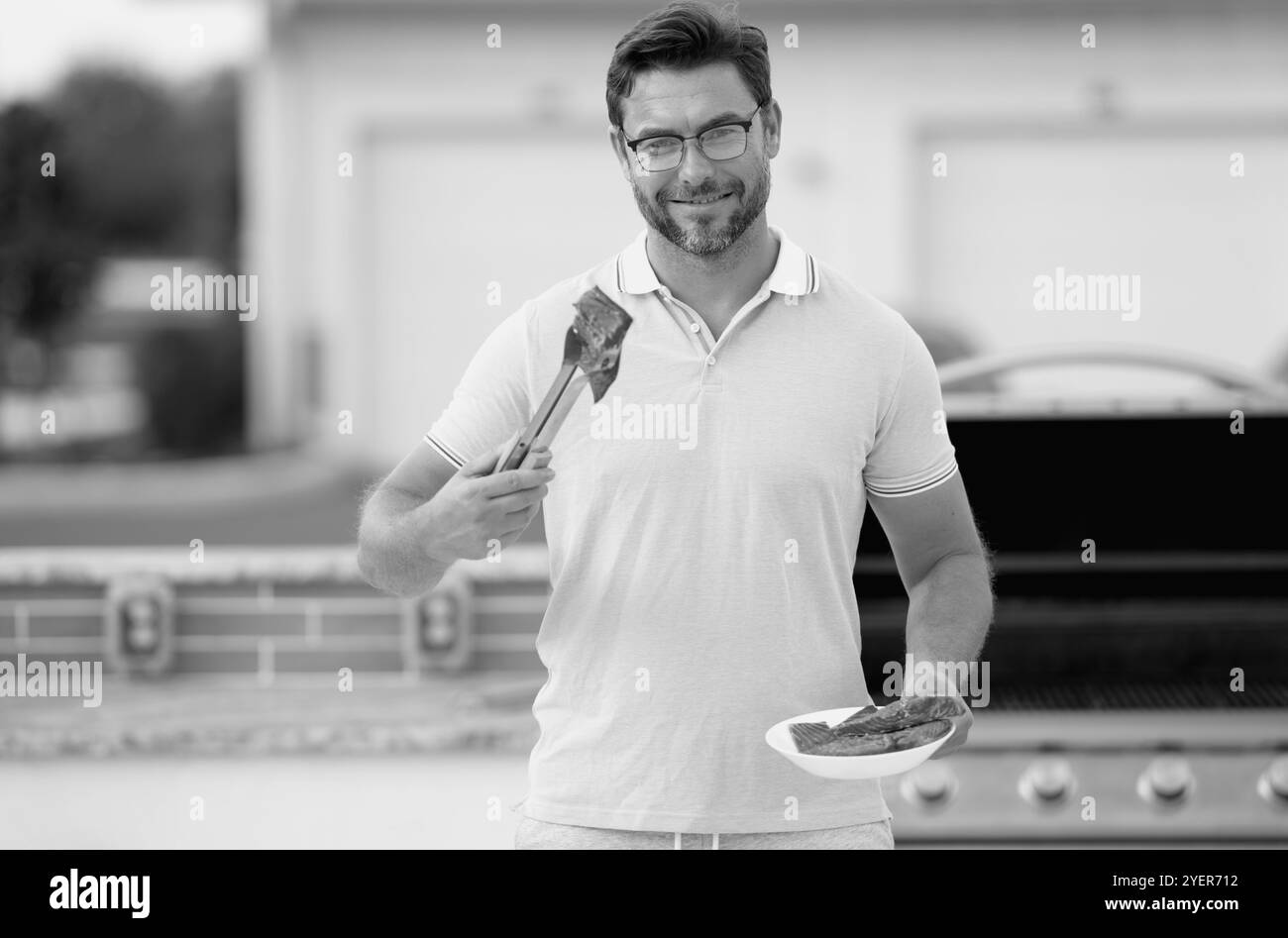 Beau homme préparant le barbecue. Un homme cuisinant du saumon sur un barbecue. Un gars cuisant du saumon sur le barbecue pour un dîner d'été en famille au Banque D'Images