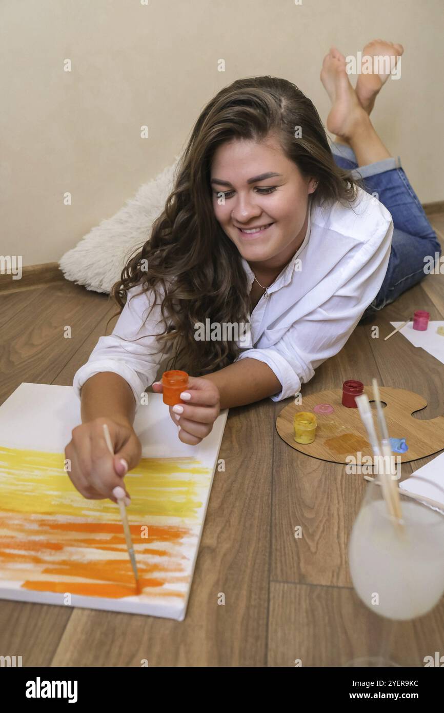 Peintre créatif dans le processus de travail. Lieu de travail de l'artiste, passe-temps, outils d'artisanat. Artiste peinture féminine de toile. La jeune femme peintre professionnelle attire dans le Banque D'Images