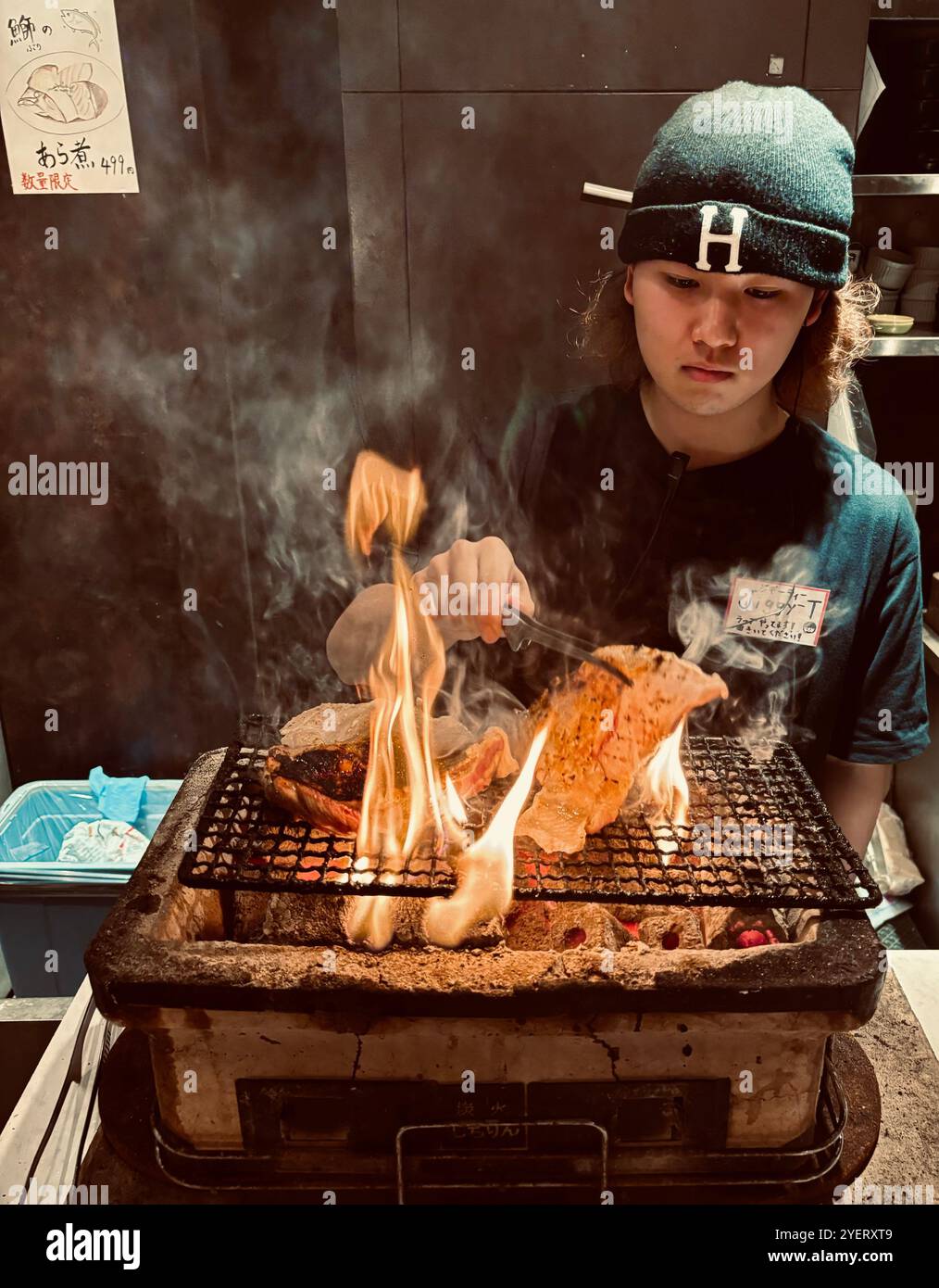Un jeune japonais grillant des brochettes au restaurant Washio Yakitori Izakaya à Chuocho, Kagoshima, Japon. Banque D'Images