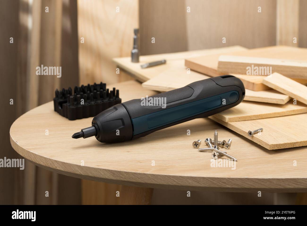 L'image présente un mini tournevis sans fil à main, entouré de diverses vis et planches en bois, soulignant son utilité dans les projets de bricolage et Banque D'Images