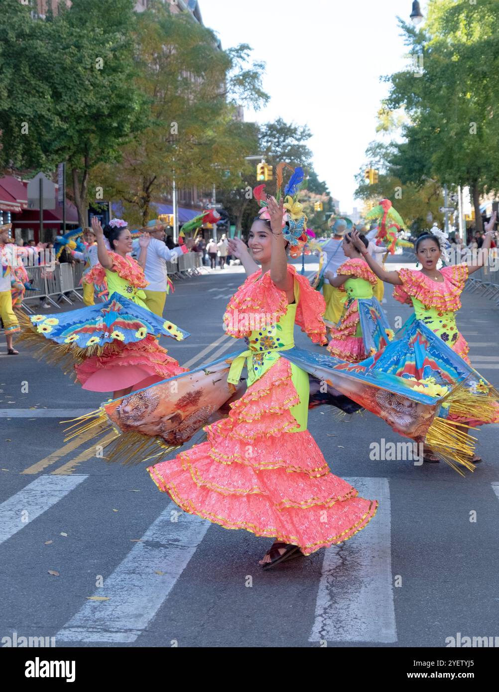 Les danseurs en robes orange colorées effectuent un parcours complexe tout en marchant dans la Parade bolivienne Day à Jackson Heights, Queens, New York. Banque D'Images