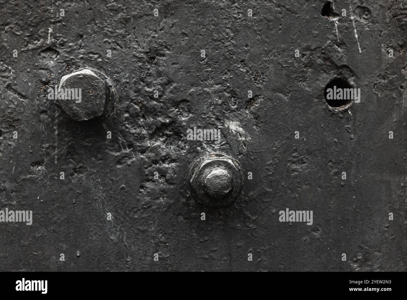Fragment de machine industrielle noire vintage, gros plan photo noir et blanc de boulons dans la plaque frontale, texture abstraite de fond de l'industrie lourde Banque D'Images