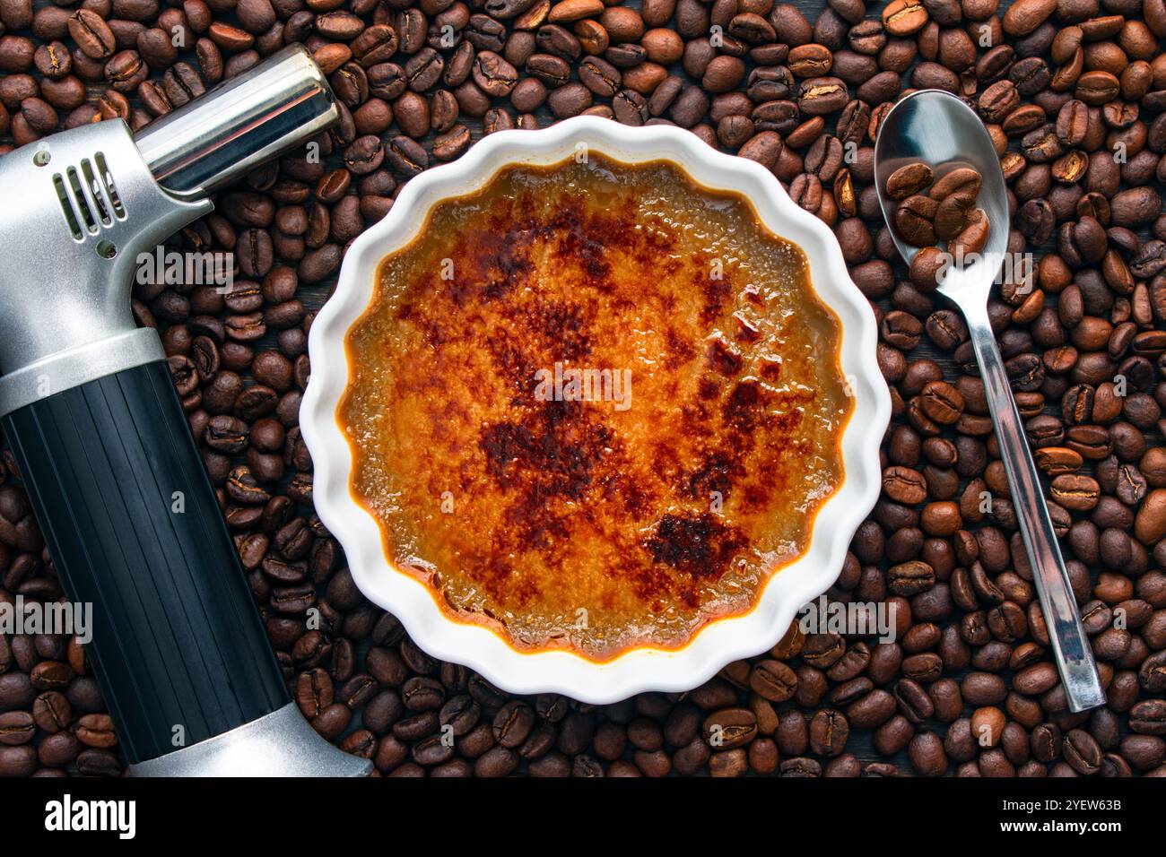 Coffee Creme Brulee Torch and Spoon entouré de grains de café : ramequin peu profond de crème brûlée au café torréfié entouré de grains de café entiers Banque D'Images