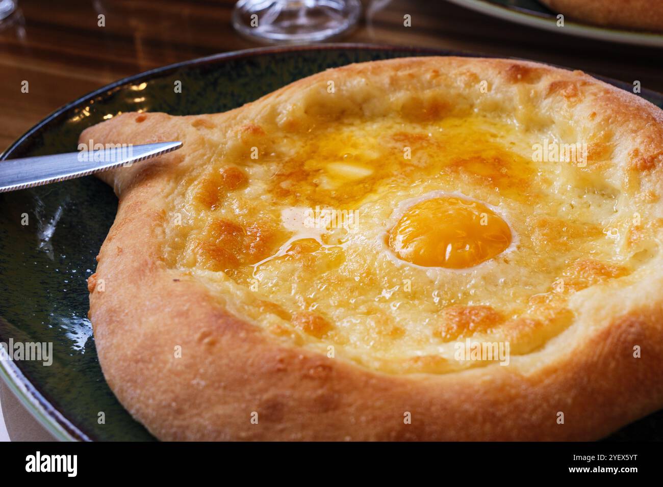 Délicieux khachapuri adjarien avec fromage fondu et un œuf sur le dessus servi chaud. Gros plan sur le khachapuri adjarien, un pain géorgien traditionnel au fromage fourré de bateau Banque D'Images