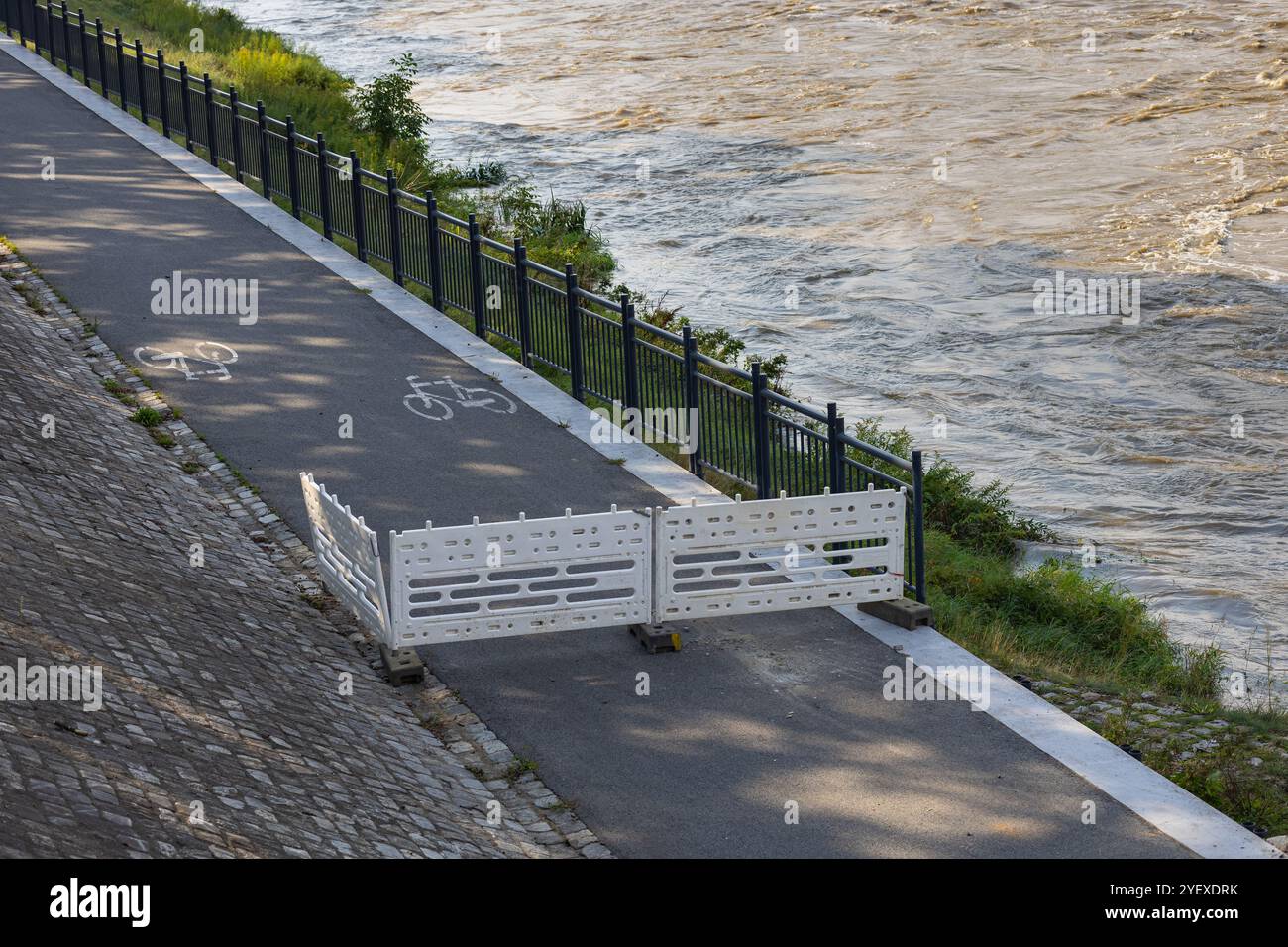 Fermeture temporaire de la piste cyclable au bord de la rivière avec des barrières de sécurité en raison de la montée des eaux lors de fortes précipitations Banque D'Images
