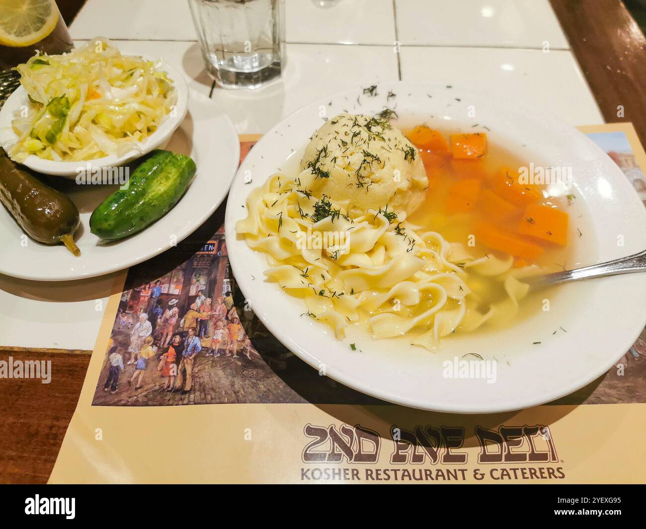 Une assiette de soupe de boule de matzah avec des nouilles, des carottes, et un côté de coleslaw et de cornichons au célèbre deli de la 2ème avenue à New York. Banque D'Images