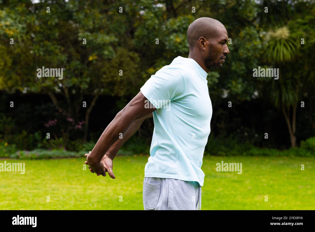 homme afro-américain étirant les bras dans le parc, profitant de l'exercice en plein air et de l'air frais Banque D'Images