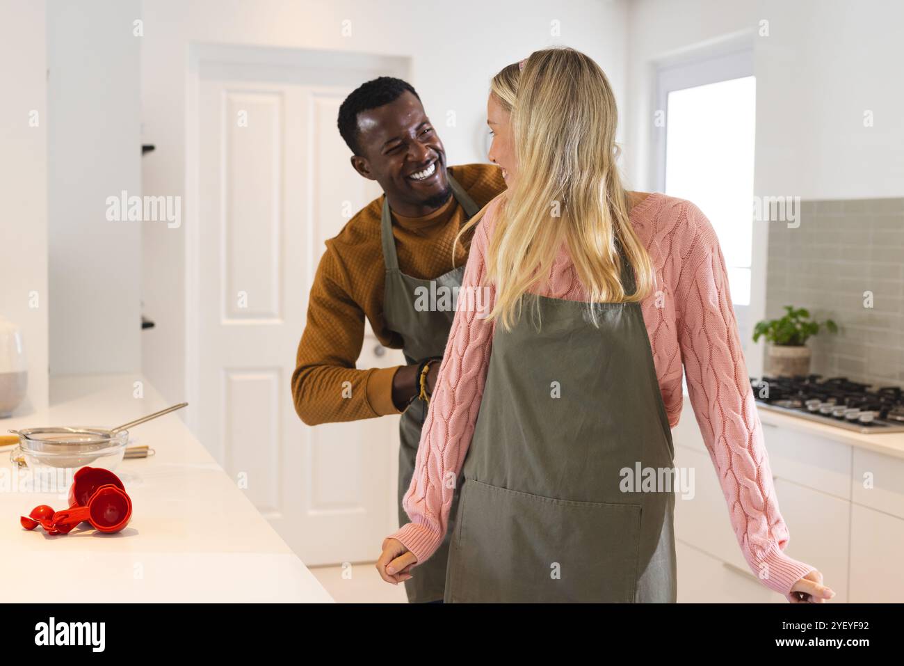 couple multiracial riant ensemble dans la cuisine tout en préparant le repas de vacances à la maison Banque D'Images