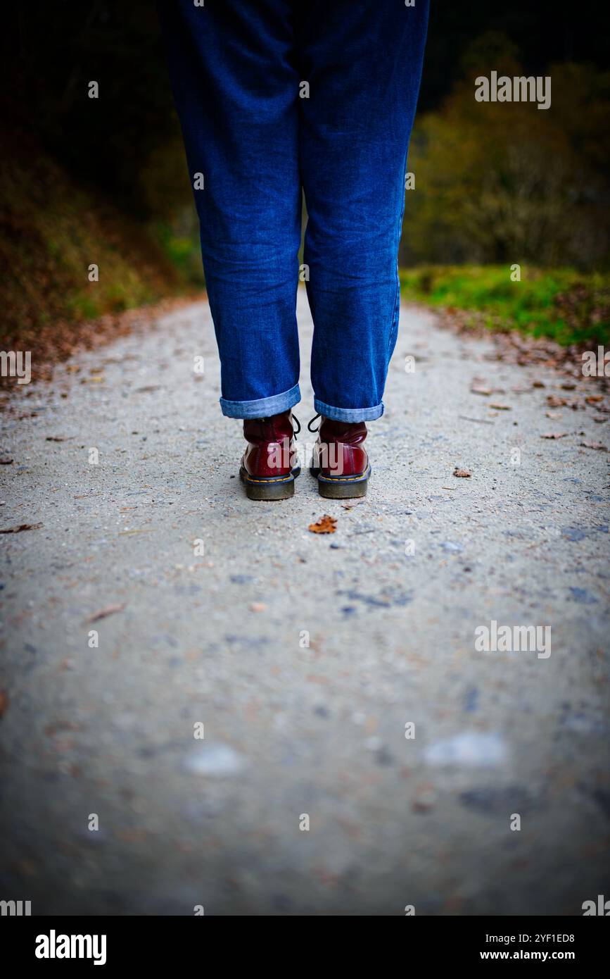 Femme en bottes rouges marchant dans les bois avec des feuilles Banque D'Images