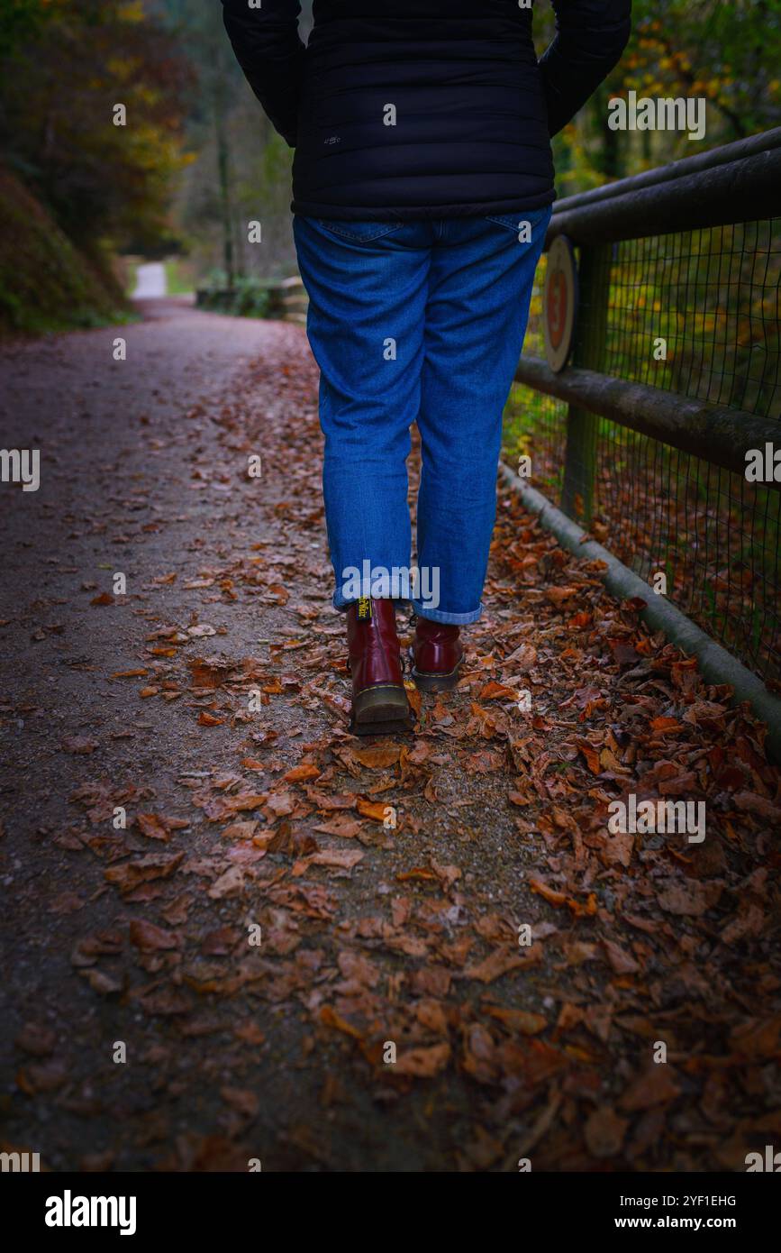 Femme en bottes rouges marchant dans les bois avec des feuilles Banque D'Images