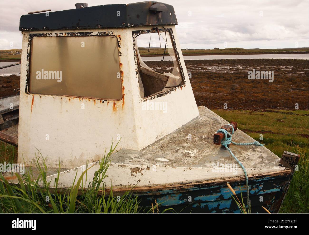 Une épave ancienne et abandonnée d'un petit bateau, avec une fenêtre cassée, au bord de la route près de la jetée à Callanish, île de Lewis, Écosse Royaume-Uni Banque D'Images